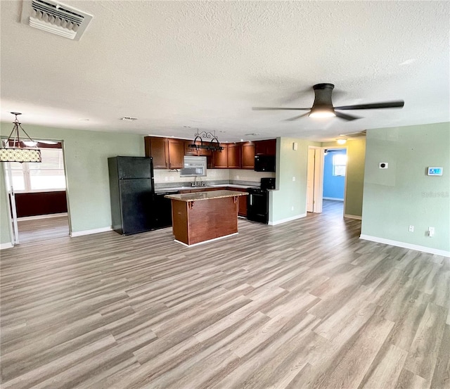 kitchen with ceiling fan, sink, black appliances, a kitchen island, and hanging light fixtures