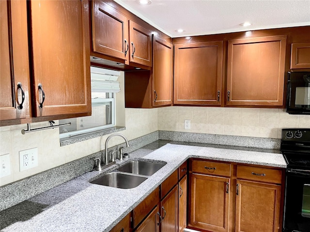 kitchen with black appliances, light stone counters, and sink