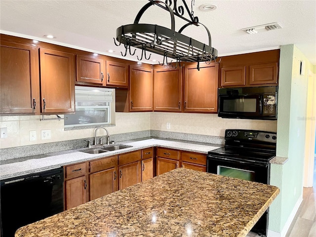 kitchen with light stone counters, sink, and black appliances