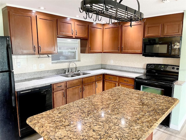 kitchen featuring black appliances, light stone countertops, and sink