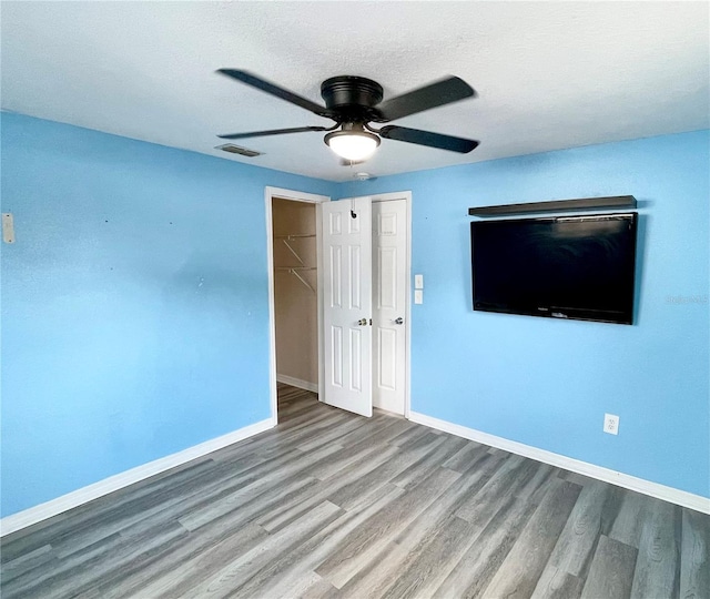 unfurnished bedroom featuring ceiling fan, hardwood / wood-style floors, and a textured ceiling