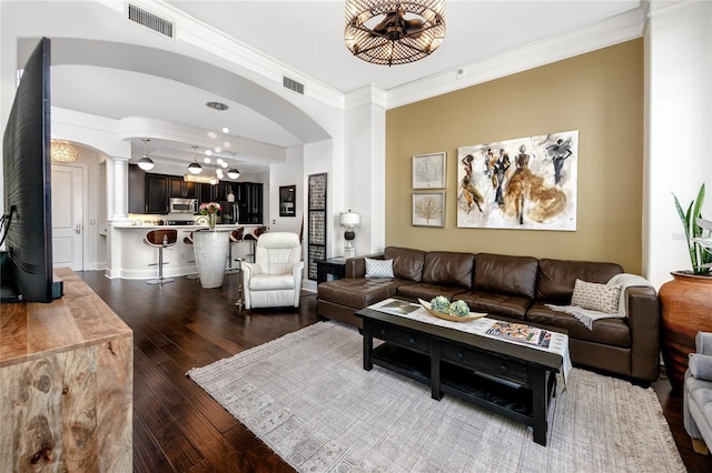 living room featuring dark wood-type flooring, ornamental molding, and ornate columns