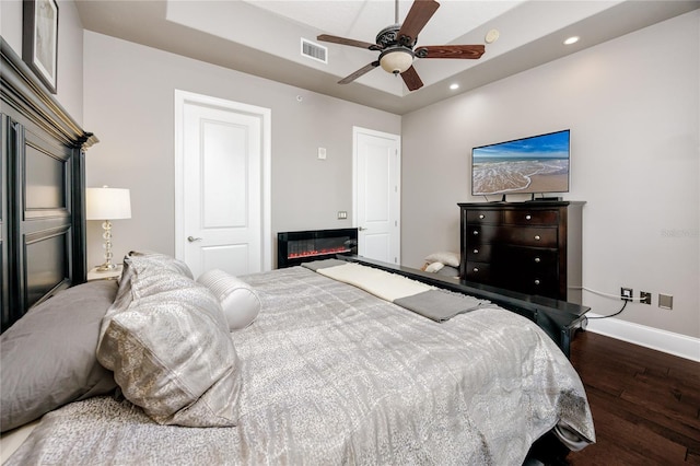 bedroom featuring ceiling fan, wood-type flooring, and a tray ceiling