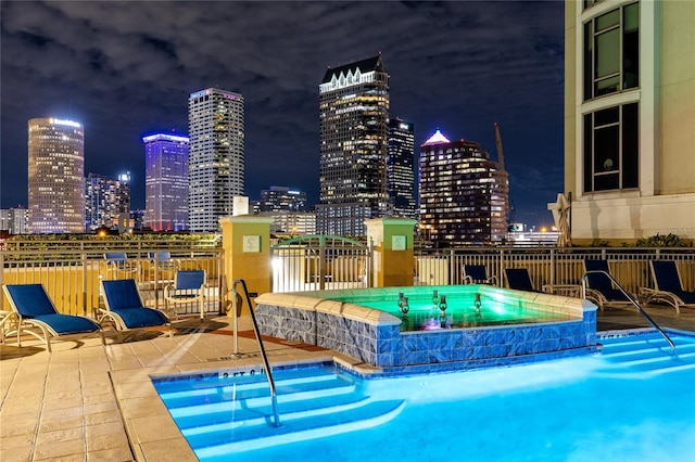 pool at twilight with a community hot tub and a patio