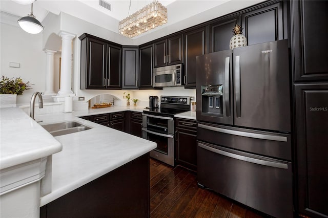 kitchen with decorative columns, stainless steel appliances, dark hardwood / wood-style floors, decorative light fixtures, and sink