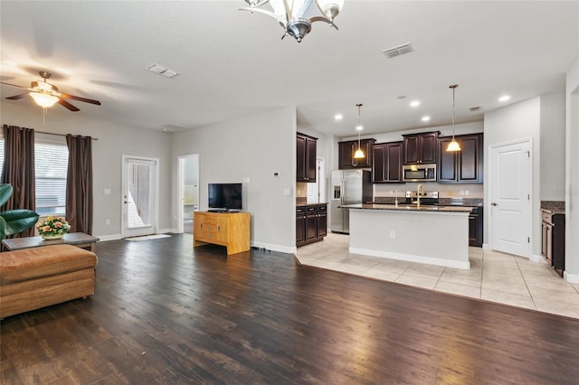 kitchen with pendant lighting, sink, a kitchen island with sink, dark brown cabinets, and stainless steel appliances