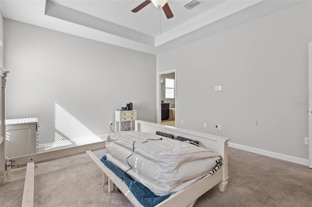 bedroom featuring a raised ceiling, light carpet, and ceiling fan