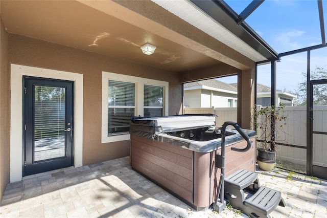 view of patio / terrace featuring a lanai and a hot tub