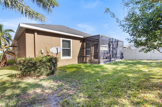 back of property featuring a lawn and glass enclosure