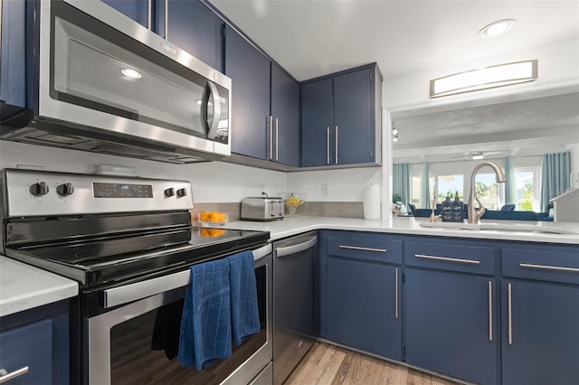 kitchen featuring blue cabinetry, appliances with stainless steel finishes, and sink