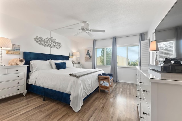 bedroom featuring wood-type flooring, a textured ceiling, and ceiling fan