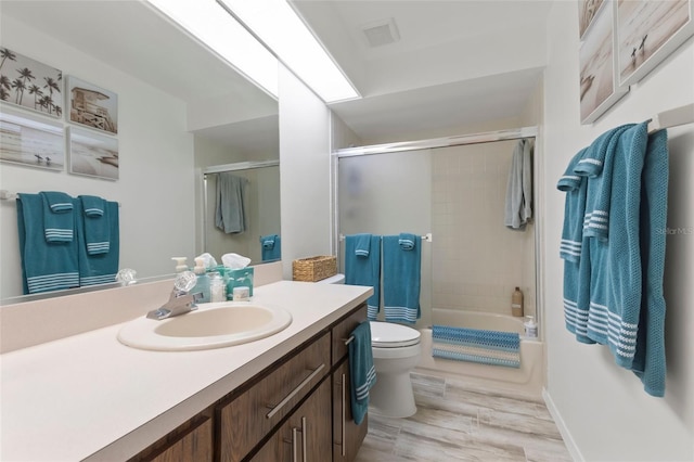 full bathroom with hardwood / wood-style floors, vanity, bath / shower combo with glass door, and toilet