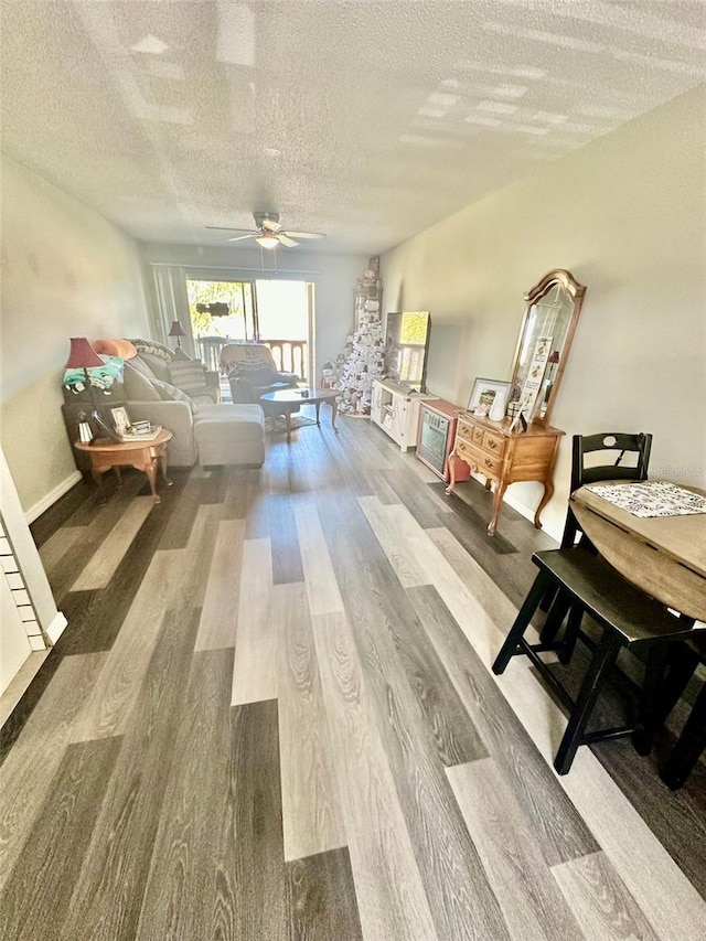 interior space featuring ceiling fan, wood-type flooring, and a textured ceiling