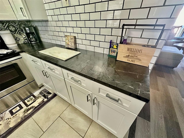 kitchen featuring tasteful backsplash, white cabinets, and dark stone counters