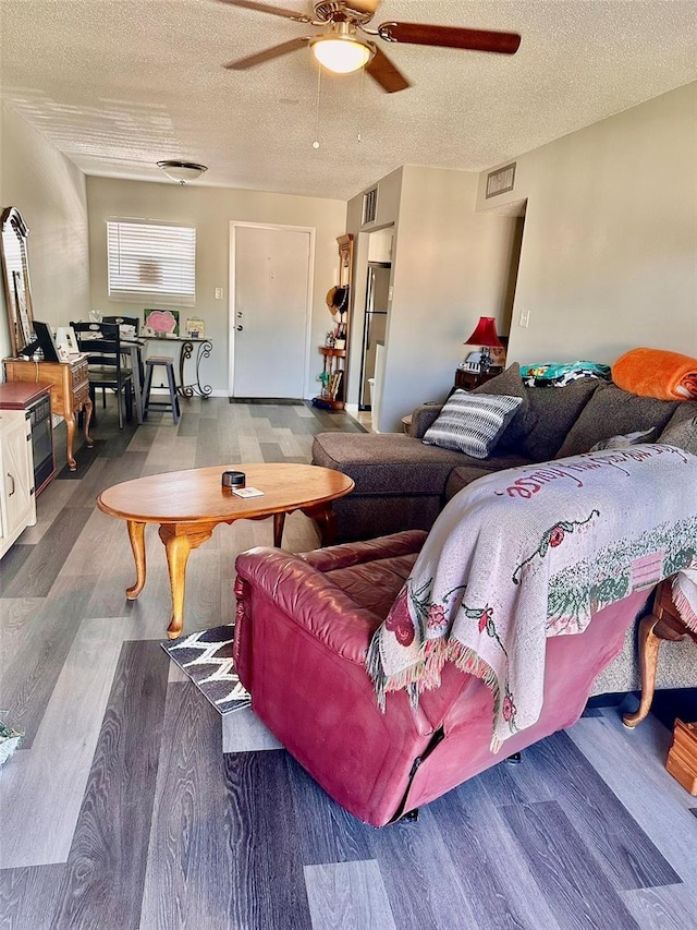 living room featuring ceiling fan, a textured ceiling, and hardwood / wood-style flooring