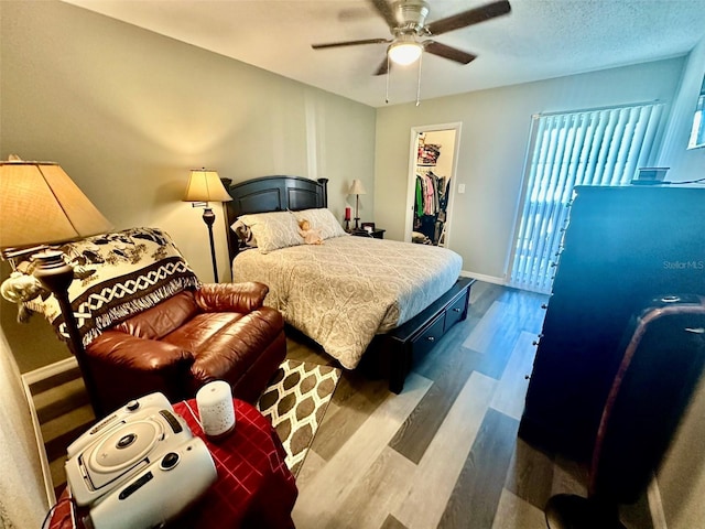 bedroom with hardwood / wood-style floors, a spacious closet, a closet, and ceiling fan