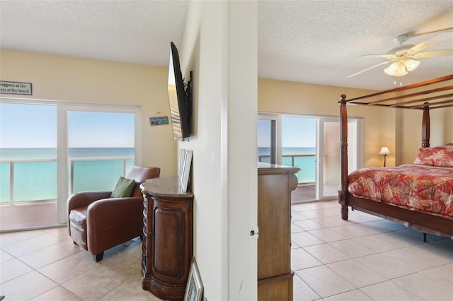 bedroom with multiple windows, ceiling fan, light tile patterned flooring, and a textured ceiling