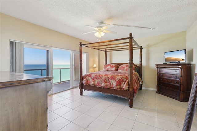 tiled bedroom with access to exterior, ceiling fan, a water view, and a textured ceiling