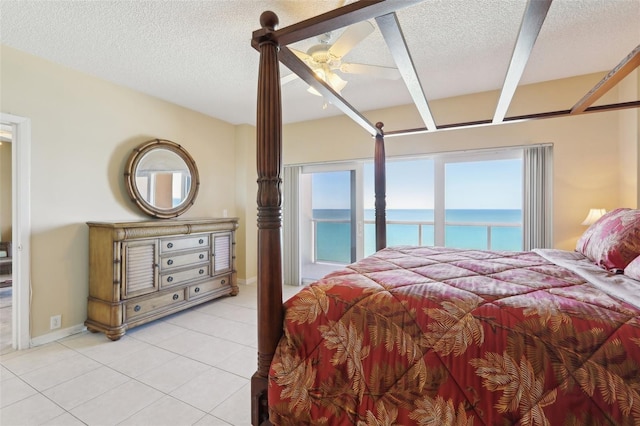 tiled bedroom featuring ceiling fan, a water view, and a textured ceiling