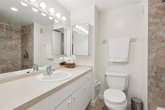 bathroom with vanity, toilet, and a tile shower