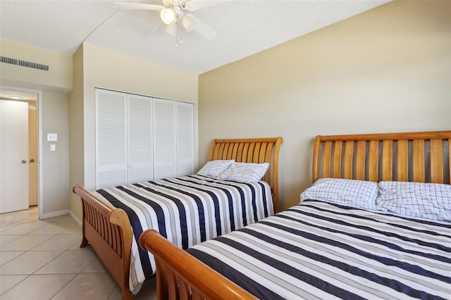 bedroom with ceiling fan, light tile patterned floors, a textured ceiling, and a closet