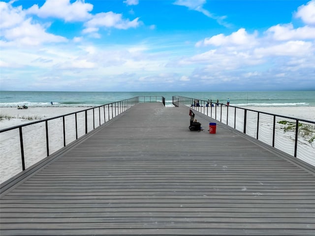 view of dock featuring a beach view and a water view