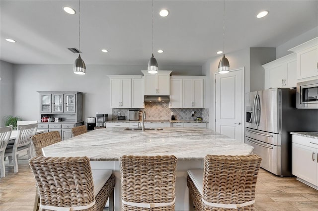 kitchen with stainless steel appliances, a center island with sink, and hanging light fixtures