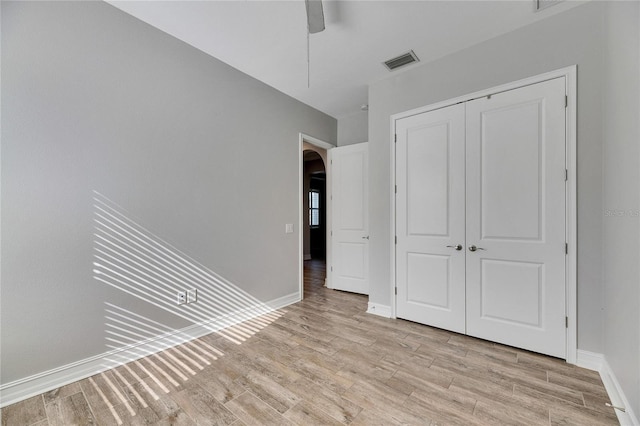 unfurnished bedroom with light wood-type flooring, ceiling fan, and a closet