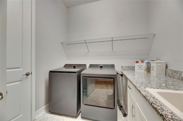 laundry area featuring independent washer and dryer, cabinets, and sink