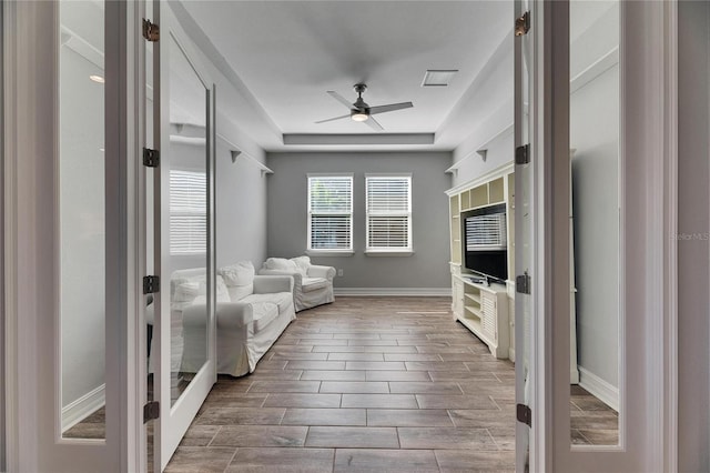 unfurnished living room with ceiling fan, french doors, and a raised ceiling