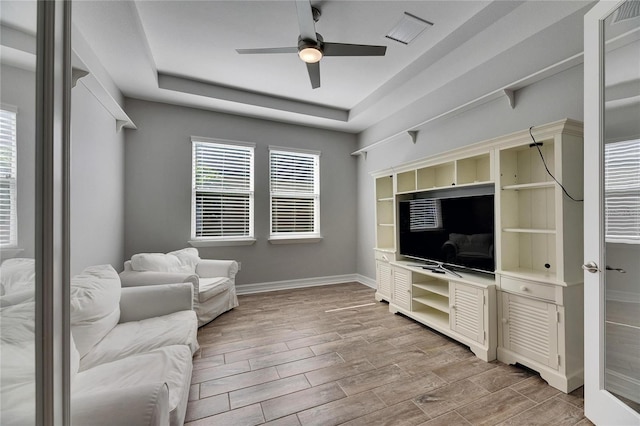 living room featuring a raised ceiling and ceiling fan