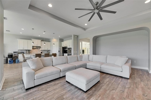 living room featuring ceiling fan and a tray ceiling