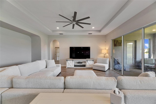 living room featuring ceiling fan, hardwood / wood-style floors, and a tray ceiling