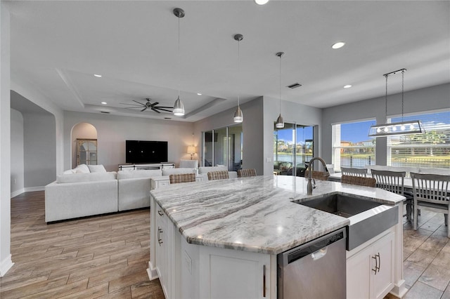 kitchen with white cabinets, decorative light fixtures, stainless steel dishwasher, and a tray ceiling