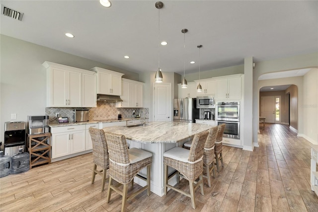 kitchen with appliances with stainless steel finishes, pendant lighting, white cabinets, and sink