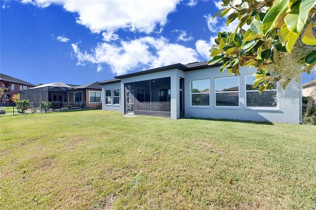 rear view of house with a sunroom and a lawn