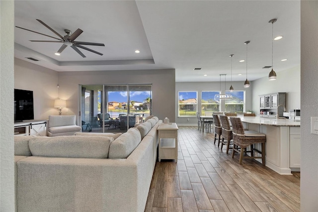 living room with a raised ceiling and ceiling fan