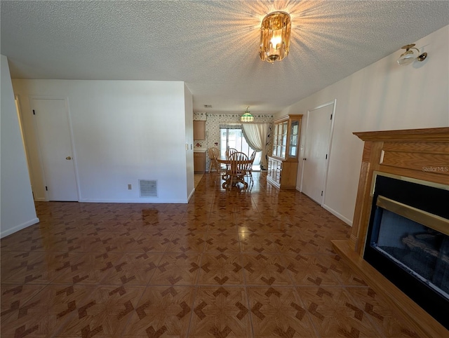 unfurnished living room featuring a textured ceiling and parquet flooring