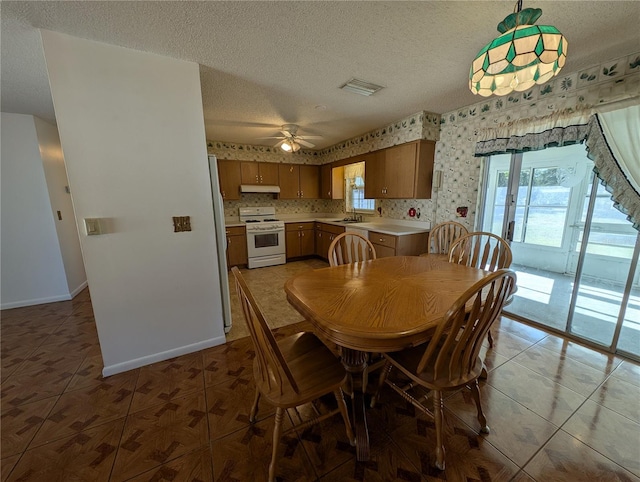 tiled dining space featuring a textured ceiling, ceiling fan, and sink