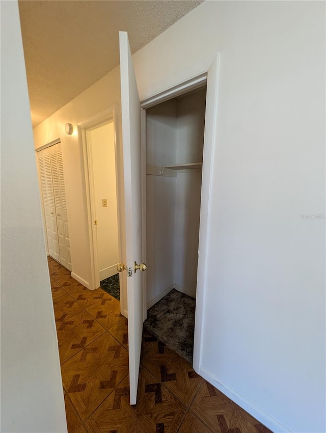 hall with dark parquet flooring and a textured ceiling