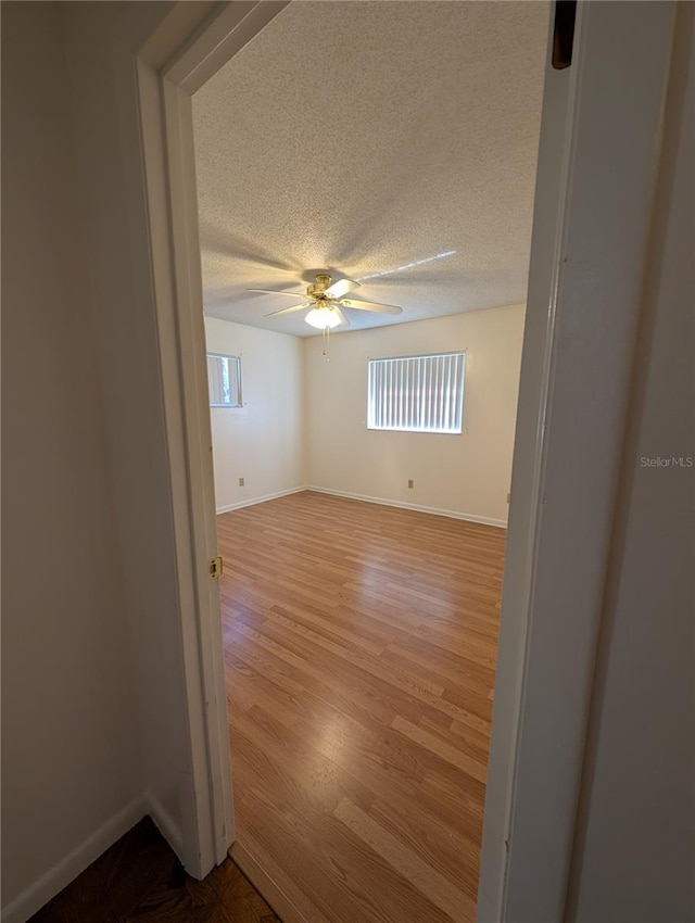 empty room with a textured ceiling, light hardwood / wood-style floors, and ceiling fan