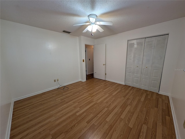 unfurnished bedroom featuring hardwood / wood-style floors, ceiling fan, a textured ceiling, and a closet