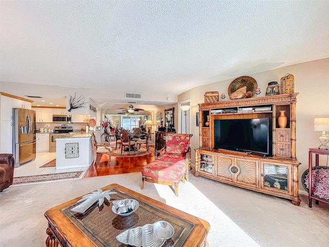 living room with ceiling fan and a textured ceiling