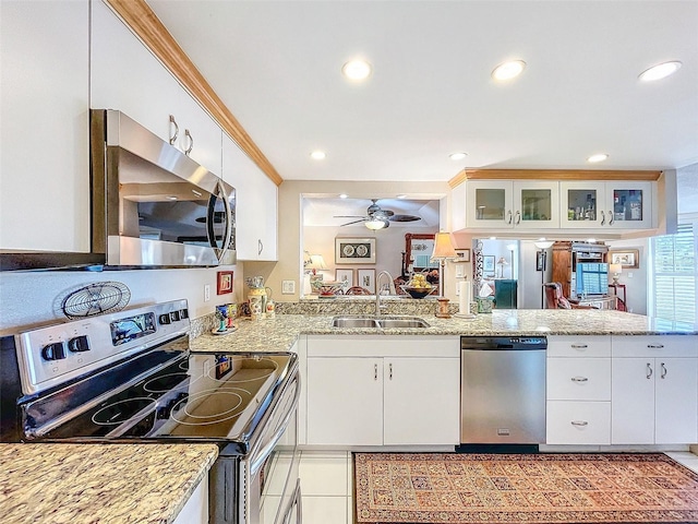 kitchen featuring kitchen peninsula, sink, light tile patterned floors, appliances with stainless steel finishes, and white cabinetry