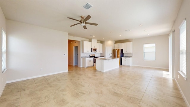 kitchen with a center island with sink, ceiling fan, white cabinets, and stainless steel appliances