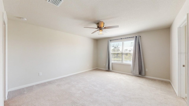 spare room featuring a textured ceiling, ceiling fan, and light carpet