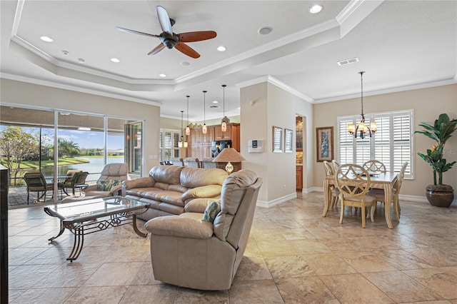 living room featuring ceiling fan with notable chandelier, a water view, crown molding, and a tray ceiling