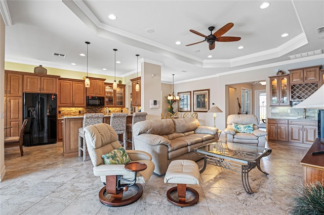 living room featuring a raised ceiling, crown molding, and ceiling fan with notable chandelier