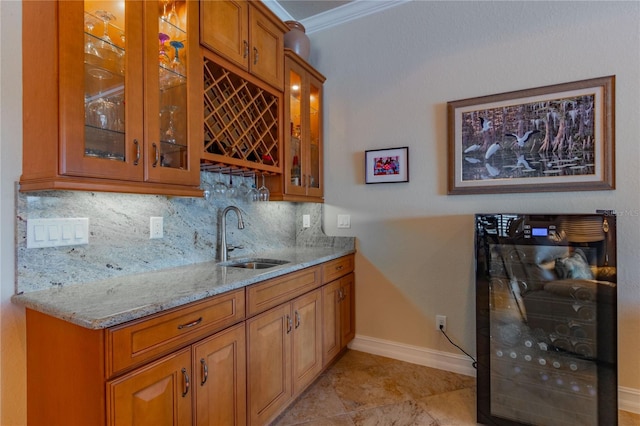 bar with tasteful backsplash, light stone counters, ornamental molding, and sink