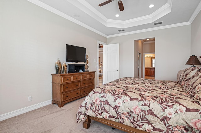 bedroom with ornamental molding, light colored carpet, a raised ceiling, ceiling fan, and connected bathroom